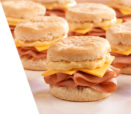 Close up of ham and cheese breakfast sandwiches served on flaky biscuits