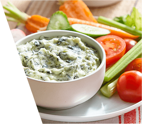 A bowl of spinach dip with fresh veggies