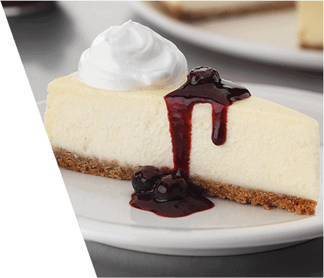 A slice of cheesecake with a dollop of whipped cream and a blueberry sauce drizzle